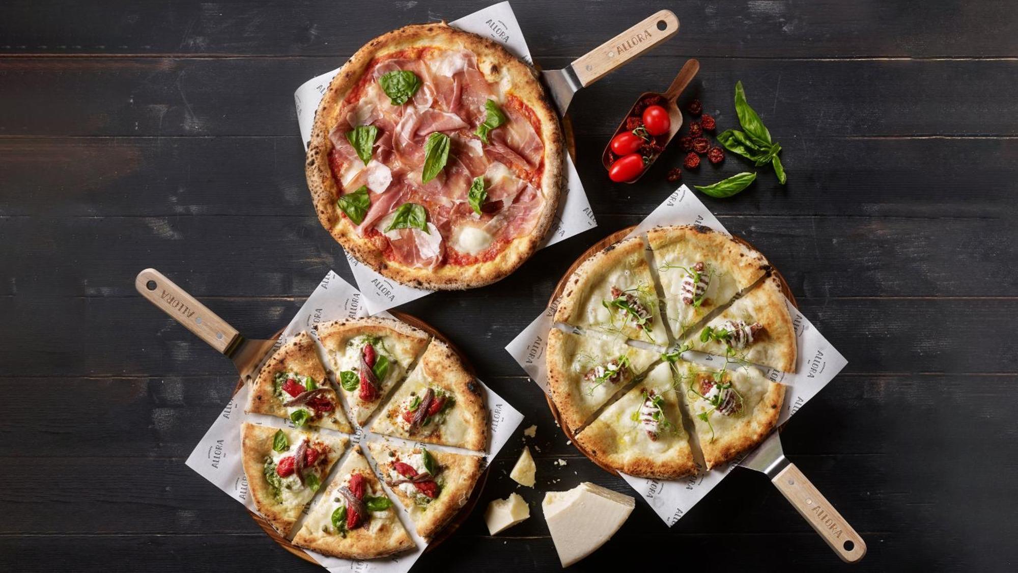 Crowne Plaza Changi Airport By Ihg Singapore Exterior foto The photo depicts three different types of pizzas on wooden serving paddles. 

1. **Top Pizza**: This pizza features a combination of thinly sliced cured meats, likely prosciutto, alongside fresh basil leaves and mozzarella cheese on a light-colored 