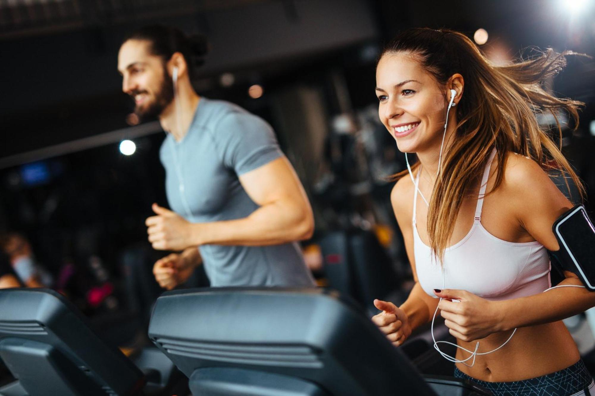 Crowne Plaza Changi Airport By Ihg Singapore Exterior foto The photo shows two individuals running on treadmills in a gym. The woman, wearing a sports bra and workout leggings, has earbuds in and is smiling as she runs. The man, next to her, wears a fitted t-shirt and appears to be focused on his workout. Bo
