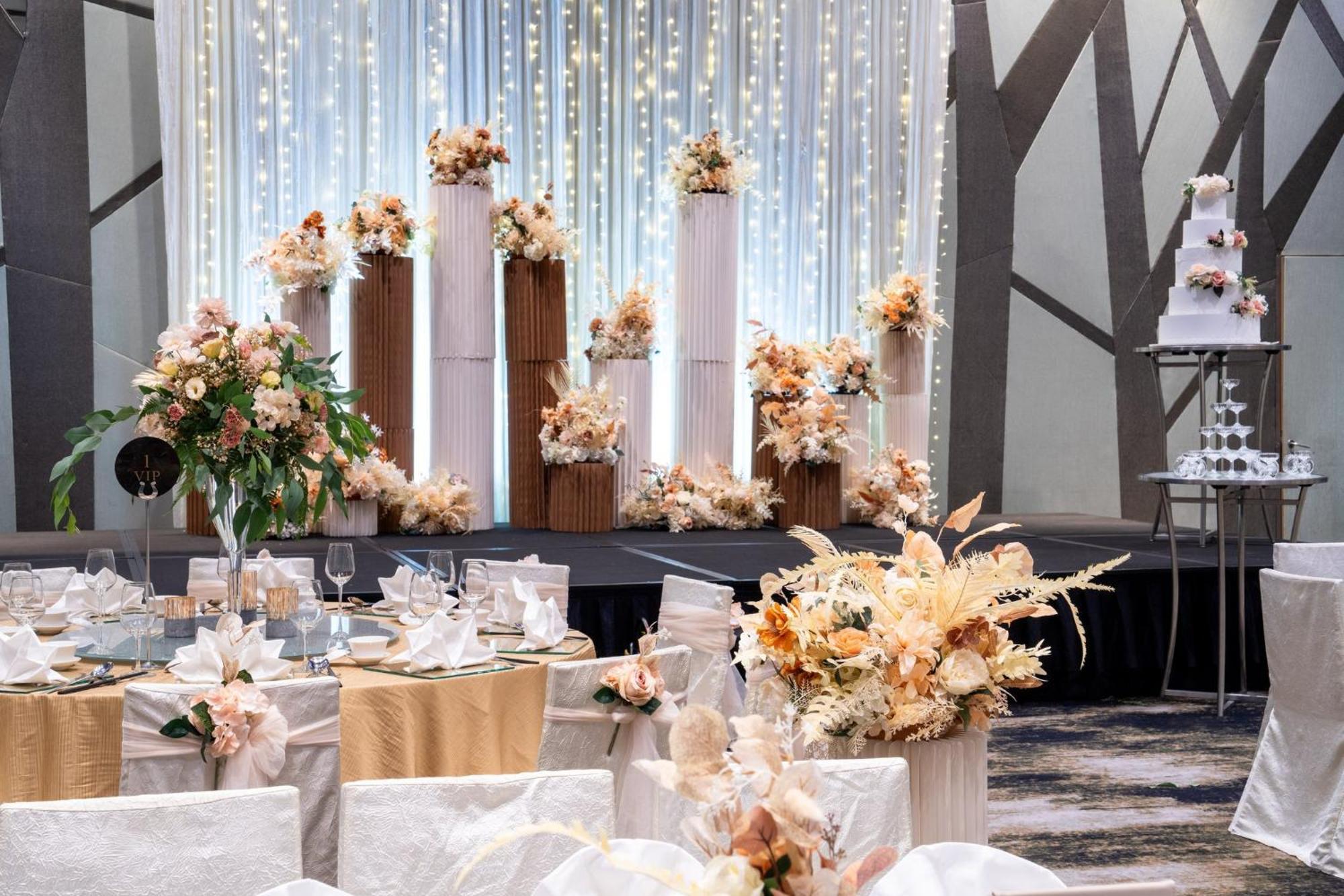 Crowne Plaza Changi Airport By Ihg Singapore Exterior foto The photo shows an elegantly decorated wedding reception. In the background, there are tall columns adorned with floral arrangements in soft, pastel colors. These floral displays are complemented by string lights hanging above, creating a romantic am