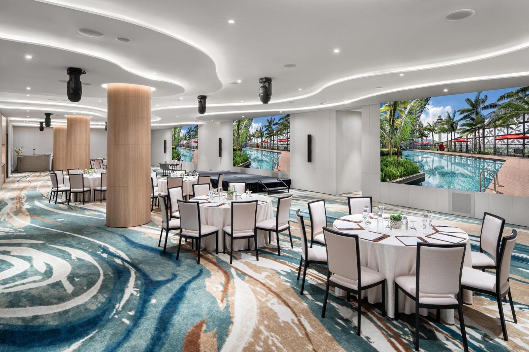 Crowne Plaza Changi Airport By Ihg Singapore Exterior foto The photo showcases a modern event space or dining area. It features several round tables covered with white tablecloths and set with dishes and utensils. The floor has an eye-catching design with swirling patterns in various shades of blue and beige