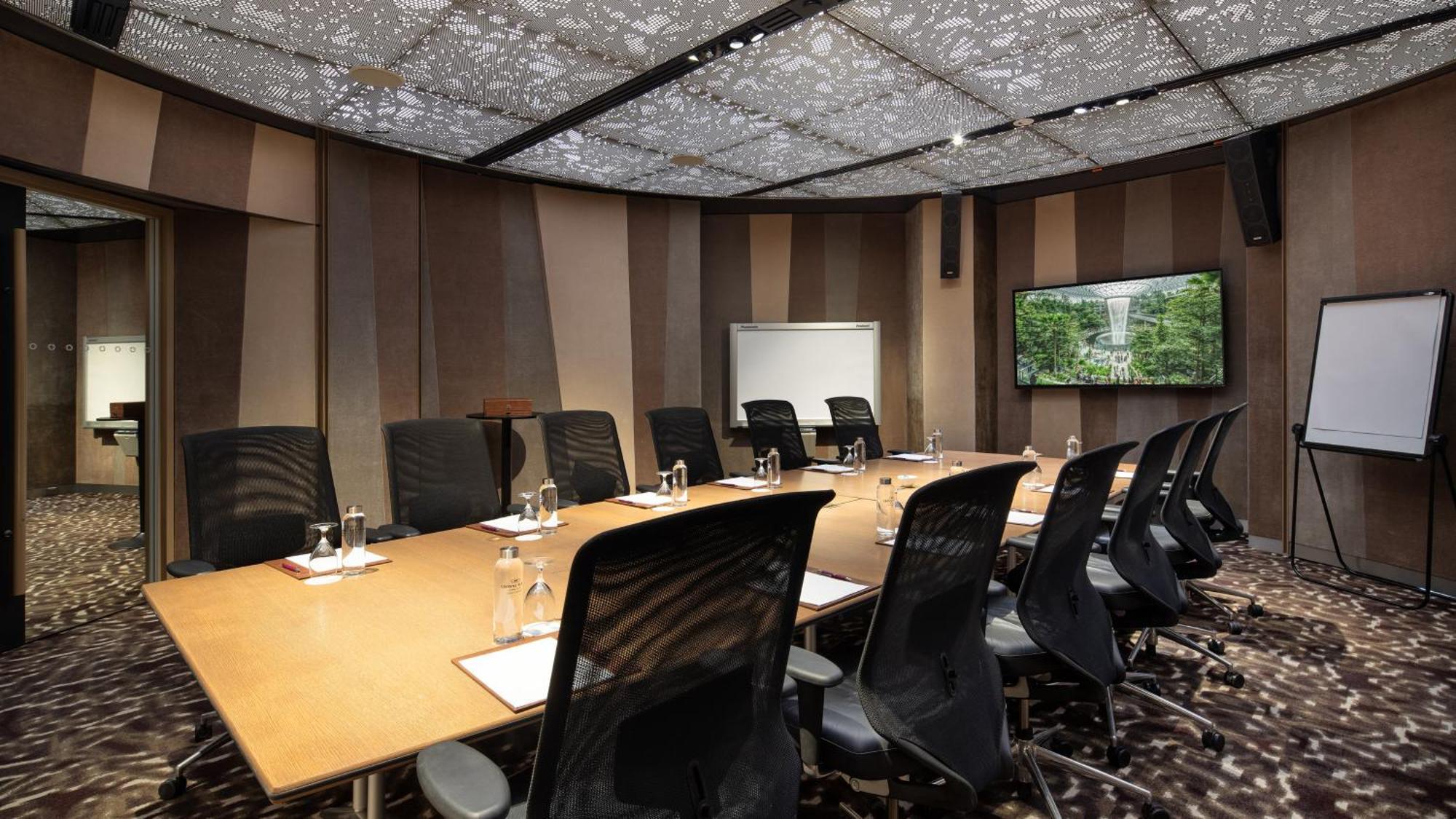 Crowne Plaza Changi Airport By Ihg Singapore Exterior foto The image shows a modern conference room. It features a large rectangular table surrounded by black ergonomic chairs. On the table, there are glasses of water, notepads, and pens. The walls have a sleek design with alternating patterns in neutral col